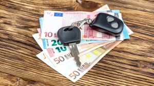 Car key with a remote fob on euro banknotes on a wooden table