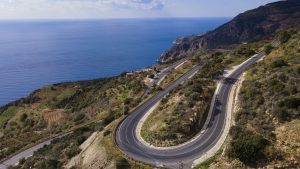 Aerial view of a winding mountain road with hairpin bends above the Mediterranean coast